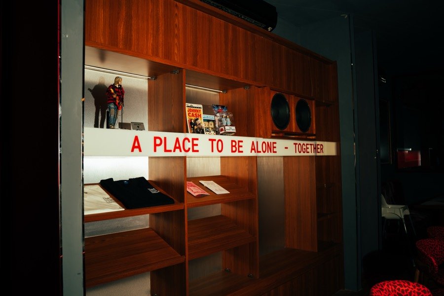 Tulisan bercahaya A Place To Be Alone—Together di dalam The Social Solitude