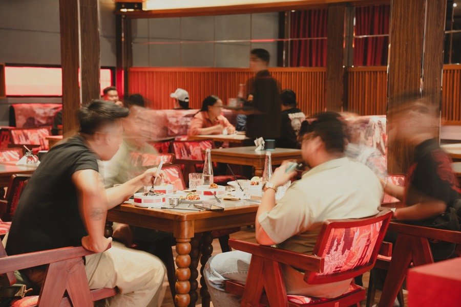Sekelompok teman berbagi meja dalam suasana malam yang hidup di The Social Solitude